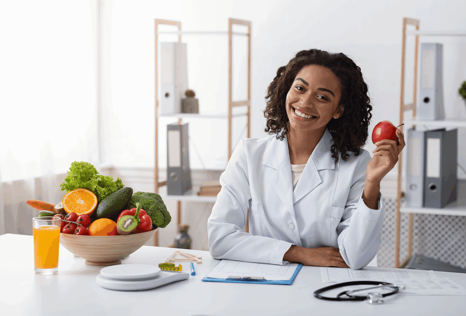 Nutritionist holding apple at desk